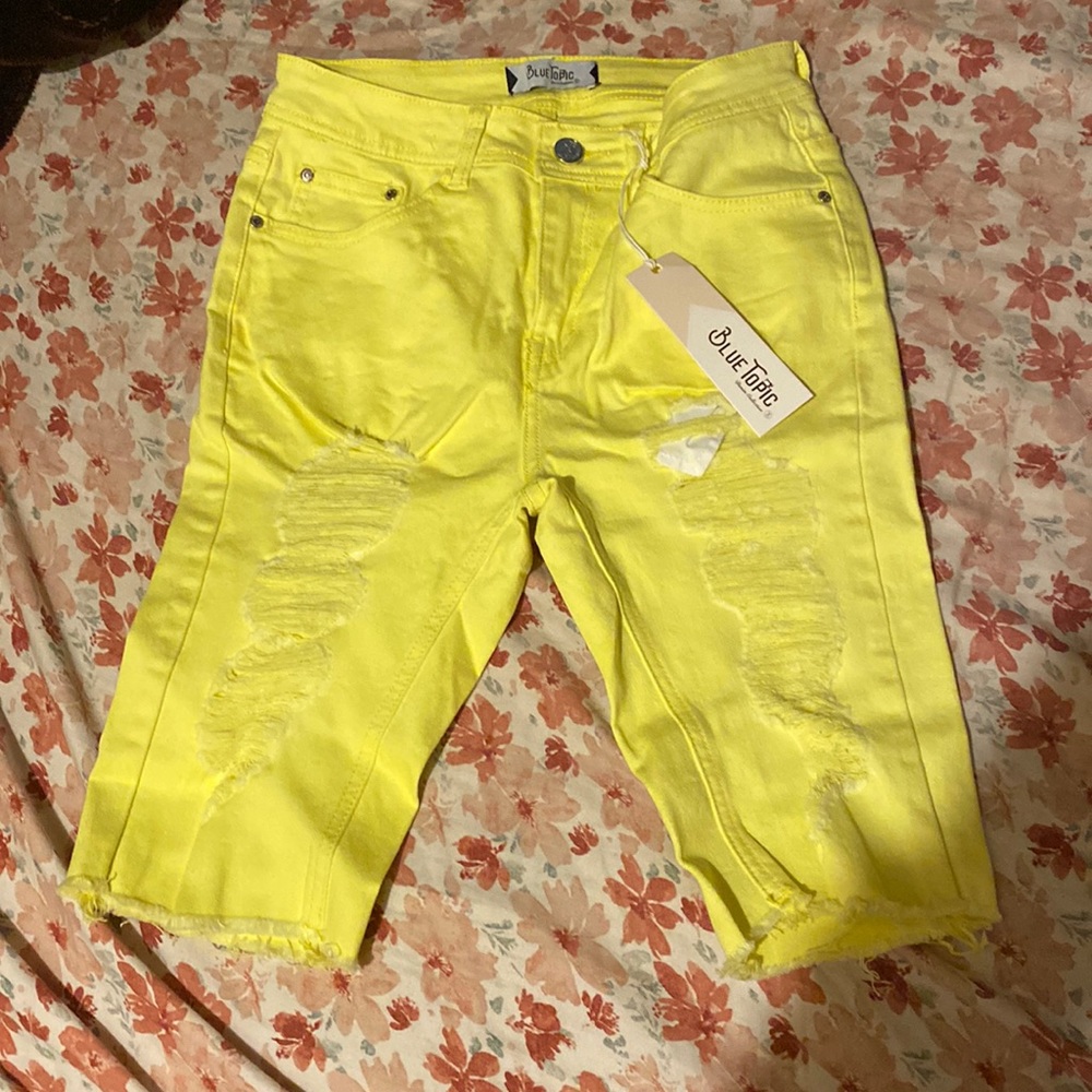 Neon yellow shorts with rips.